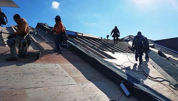 workers installing a roof under a blue sky